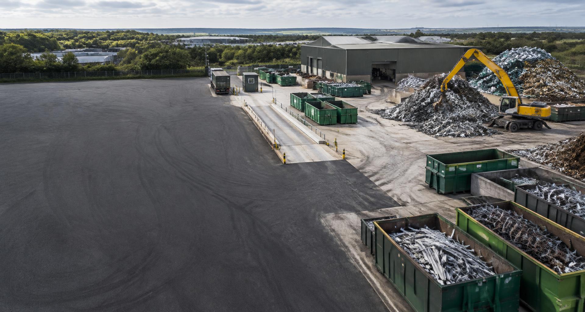 Organised metal recycling yard with material handling equipment and segregated skips